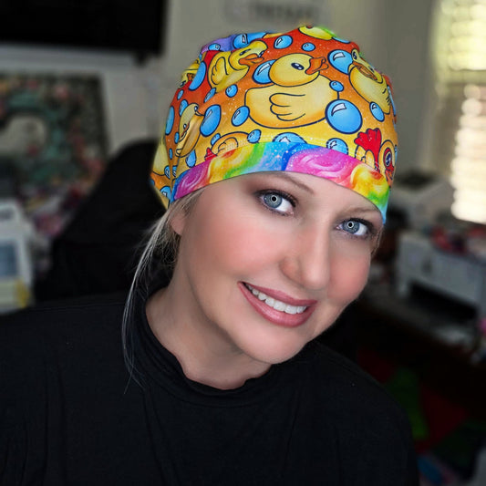 A smiling female healthcare professional wearing a colorful, full coverage ducks and bubbles medical scrub cap that completely and comfortably secures her hair.