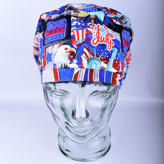 Full coverage July 4th scrub cap with patriotic American flag and fireworks print on a blue background, shown on a mannequin to demonstrate fit.