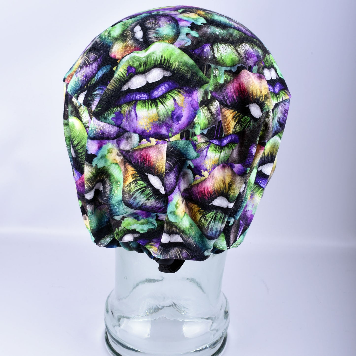 Rear view of a colorful lips print scrub cap showcasing the encased elastic band and a durable black cord-lock toggle for an adjustable, custom fit.