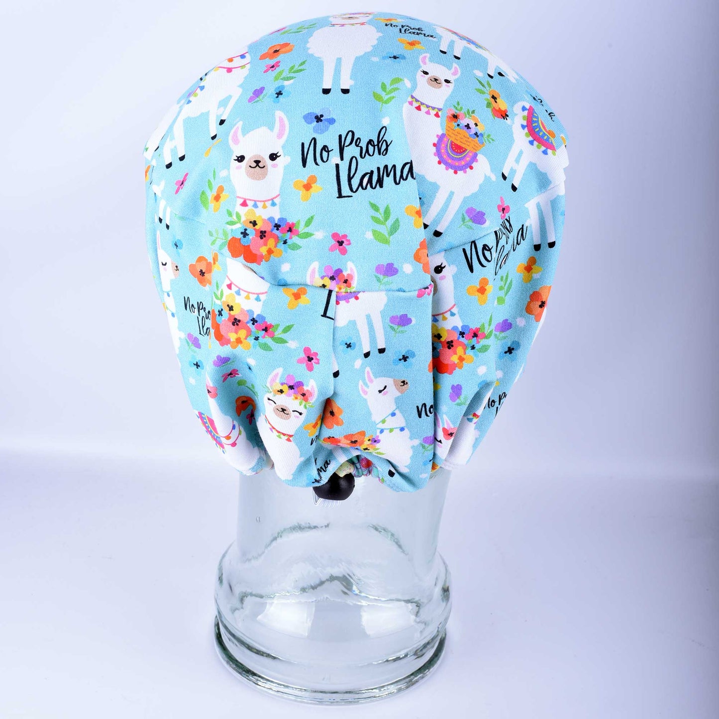 Close-up of the adjustable elastic back and heavy-duty cord lock toggle on a floral llama print surgical cap.