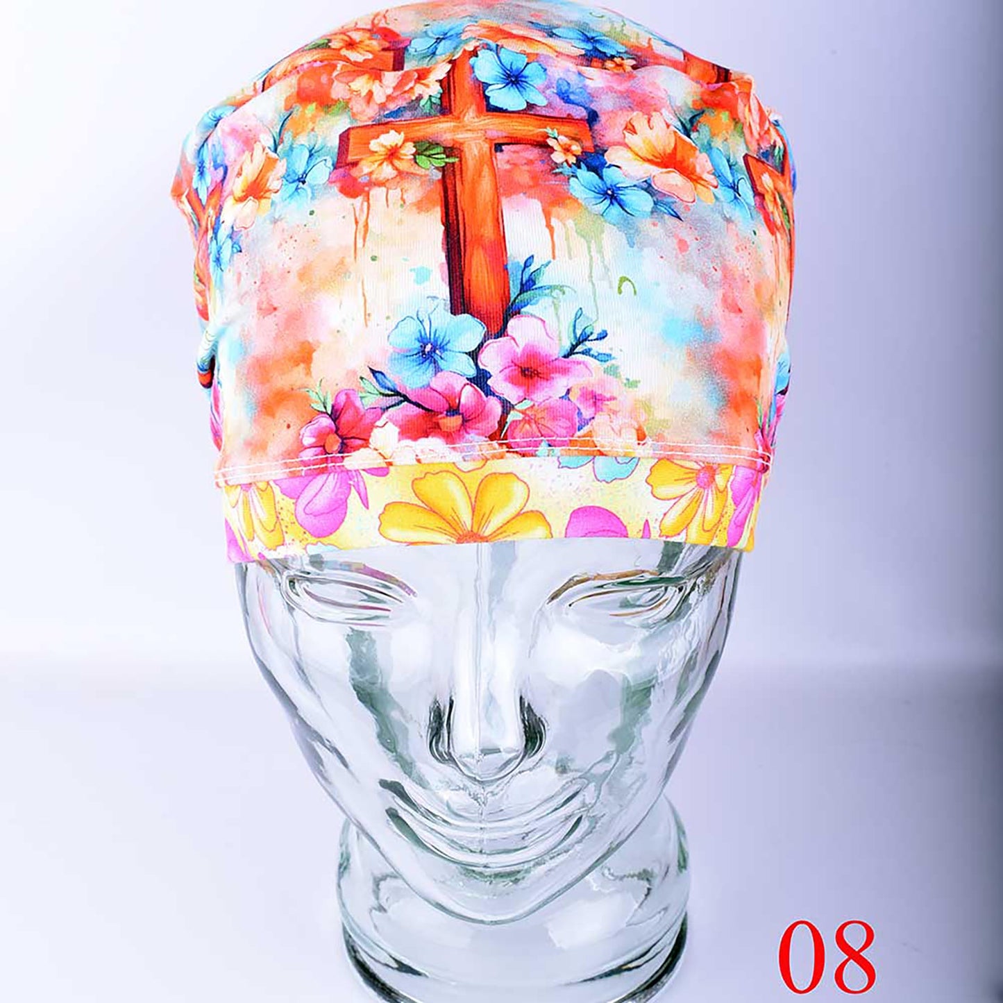 Colorful floral and watercolor cross patterned euro style scrub cap displayed on a glass mannequin head.