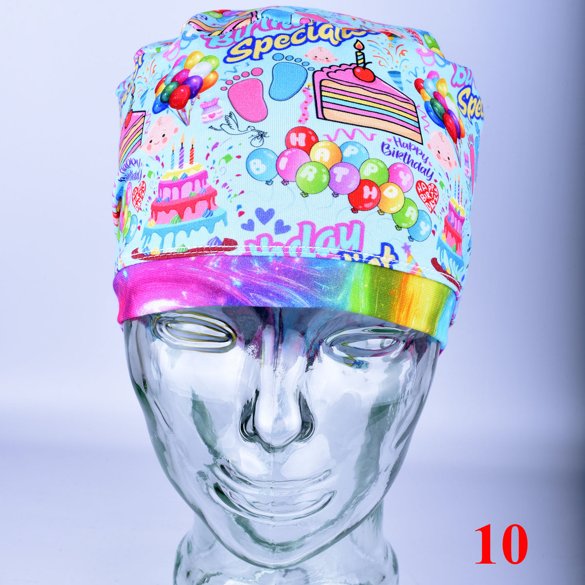 Euro-style scrub cap featuring a colorful "Birthday Specialist" cake and balloon print on a white background, shown on a mannequin head.