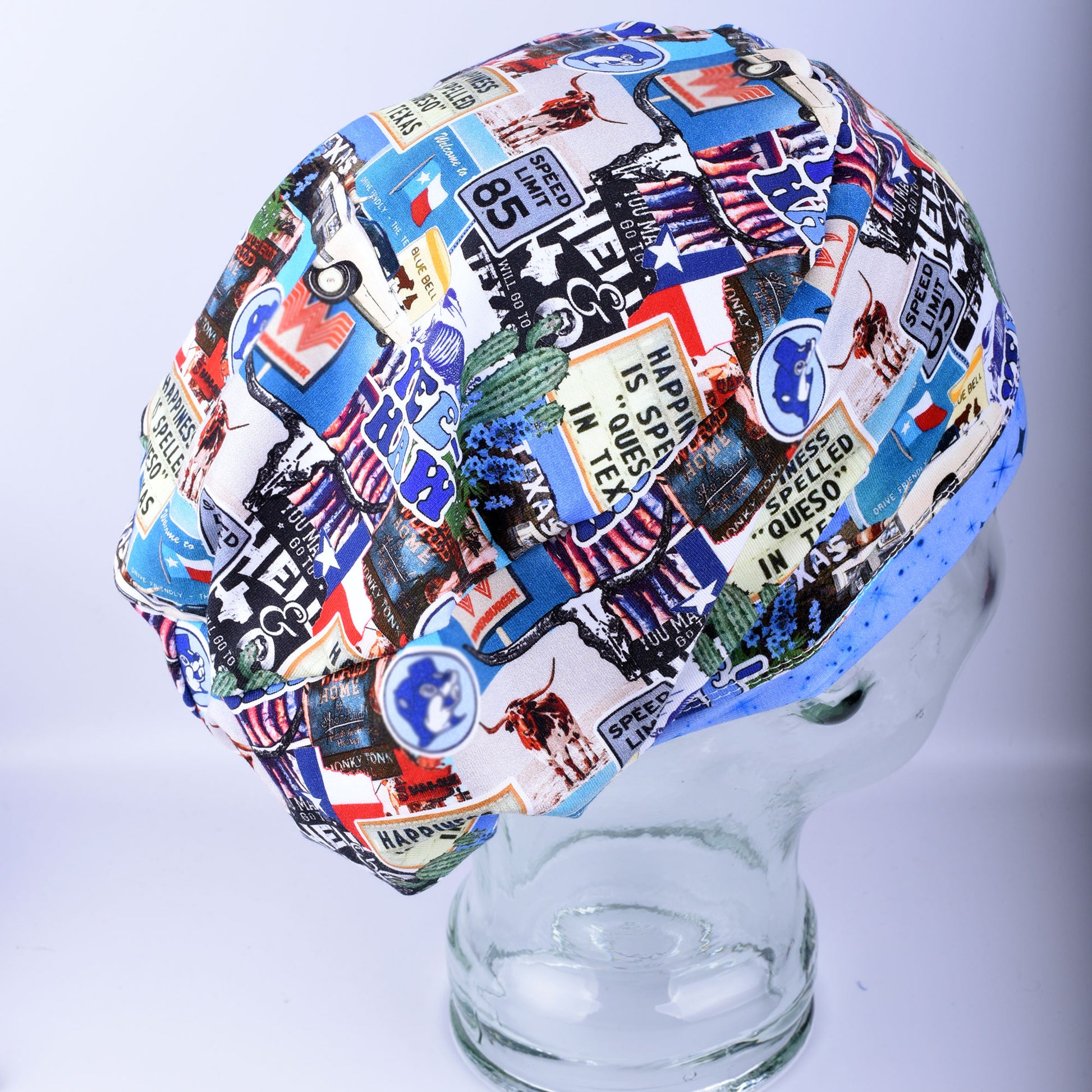 A multicolor scrub cap with a collage print of vintage Texas license plates, flags, and medical-themed graphics, displayed on a clear glass mannequin head against a light gray background.