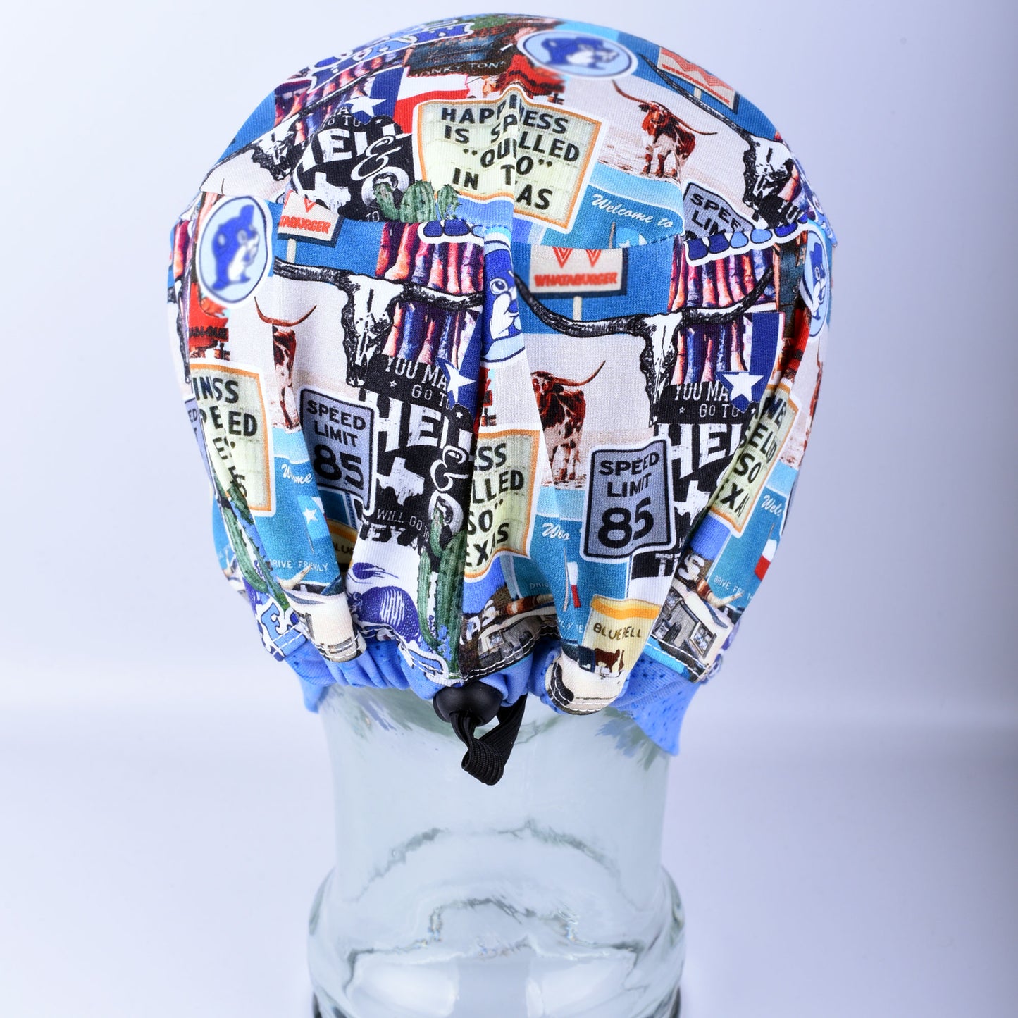 Back view of the Blue Texas scrub cap on a clear display head, showing the encased elastic band and adjustable cord lock toggle for a secure fit.