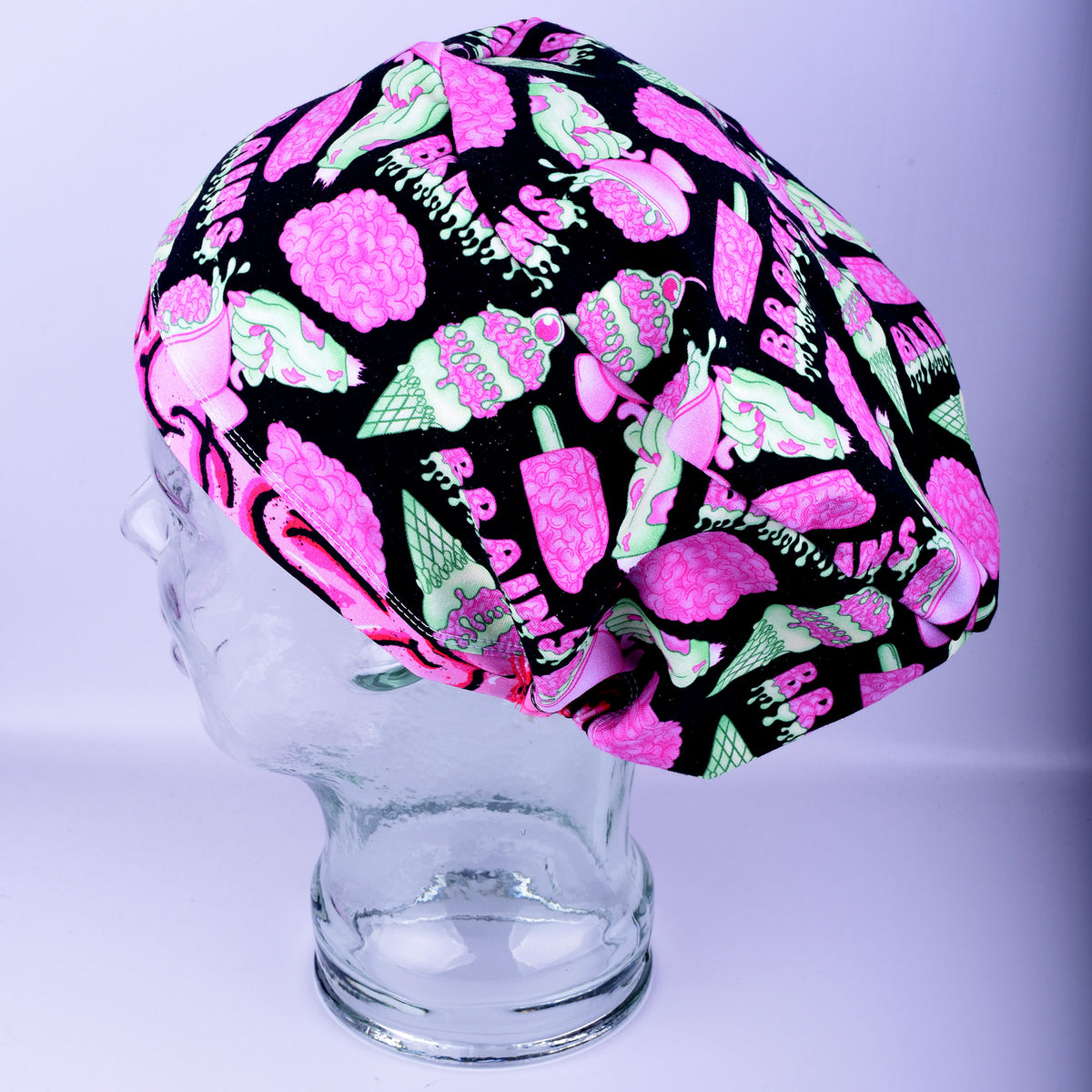 Side profile of a full-coverage scrub cap featuring a vibrant pink and black brain print on a white fabric background.