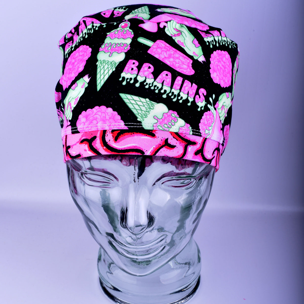 Front view of a white, black, and pink brain-patterned scrub cap on a display mannequin.
