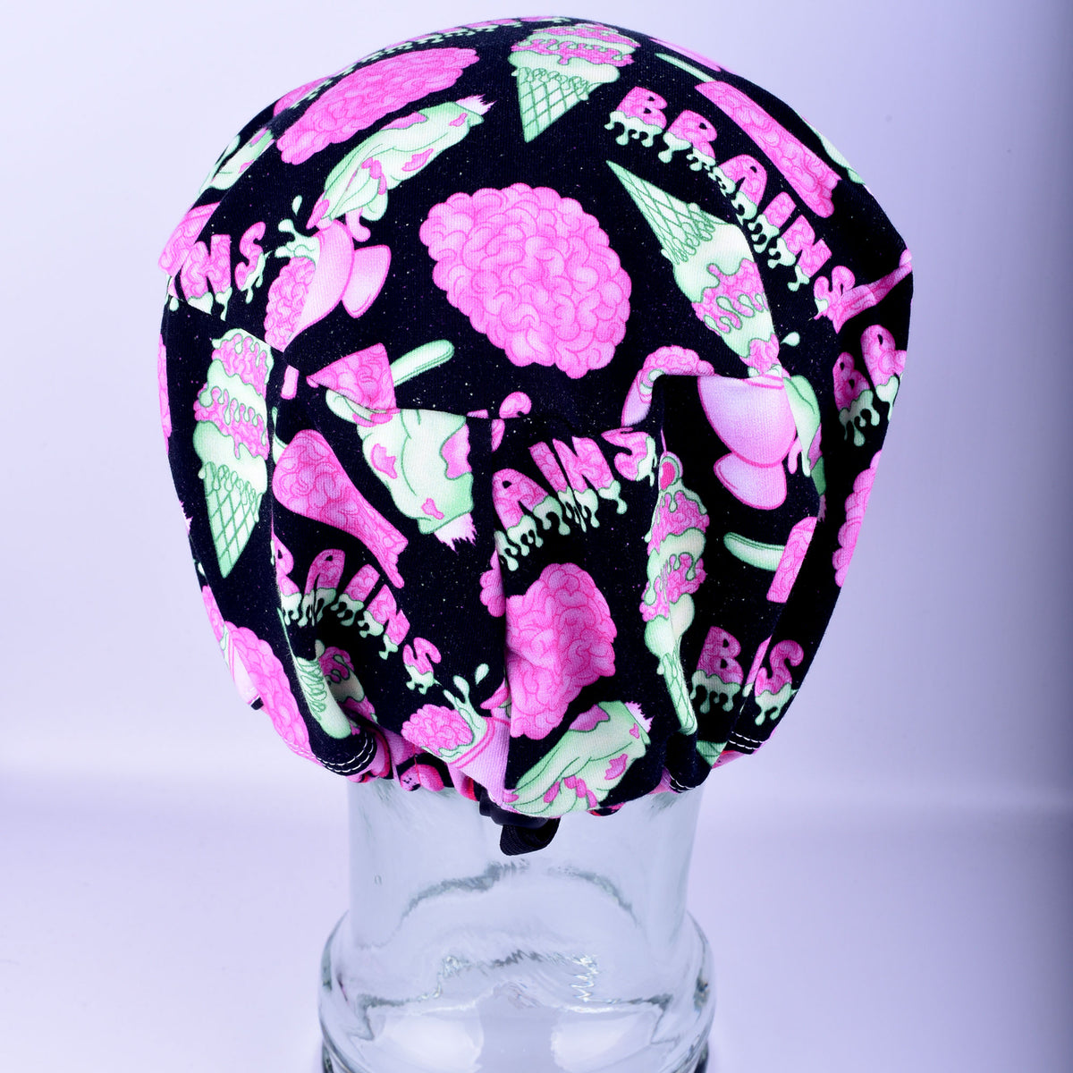 Back view of a brain-print scrub cap showing the elastic back with an adjustable black cord-lock toggle and drawstring closure.