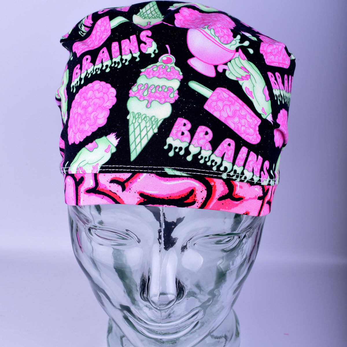 Front view of a white, black, and pink brain-patterned scrub cap on a display mannequin.