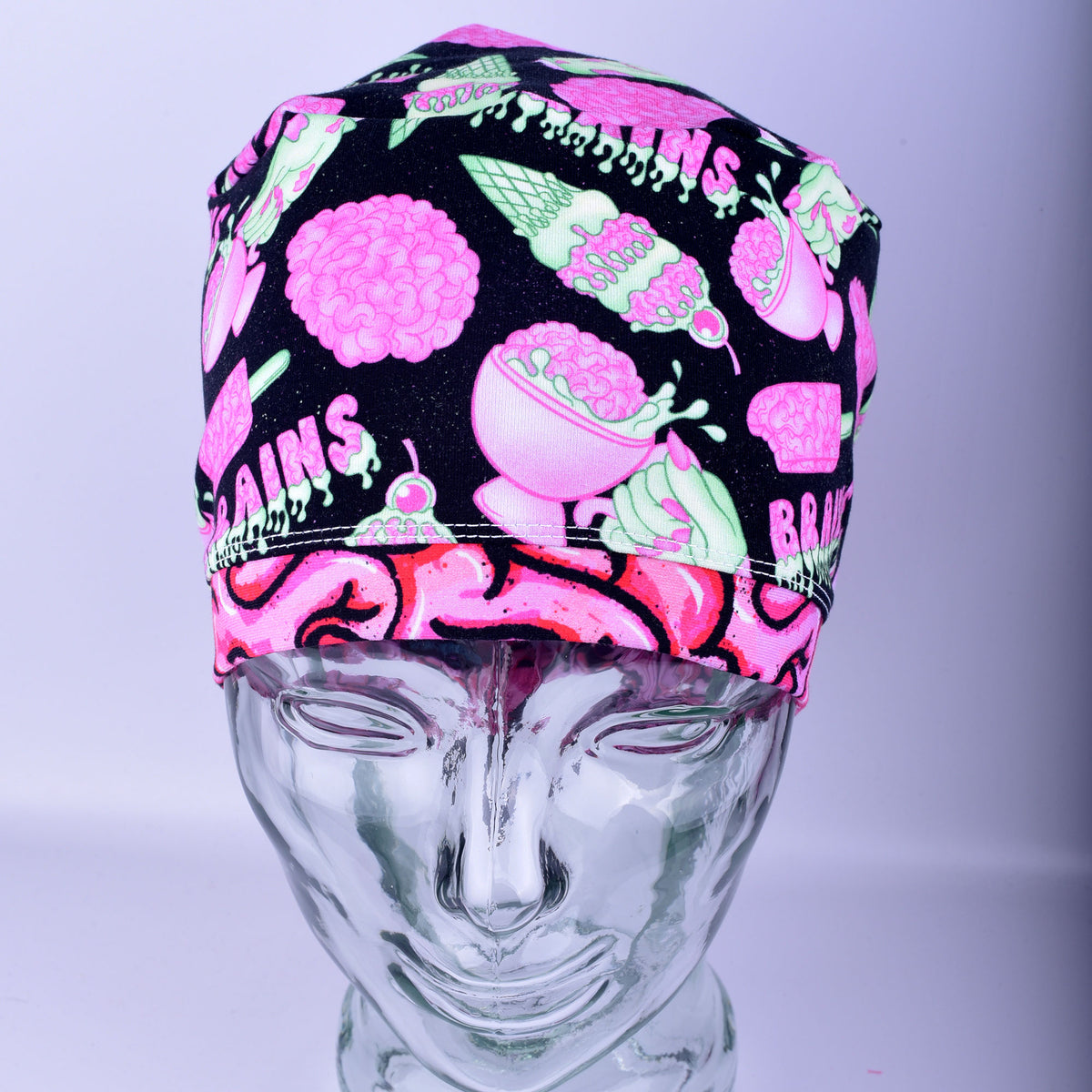 Front view of a white, black, and pink brain-patterned scrub cap on a display mannequin.