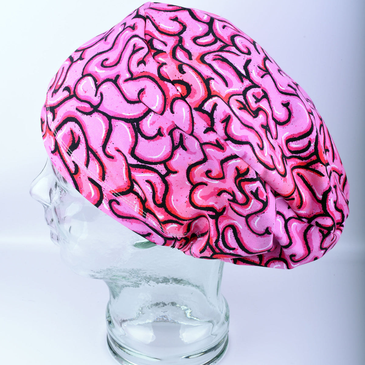 Pink brain scrub cap on a glass mannequin head against a white background