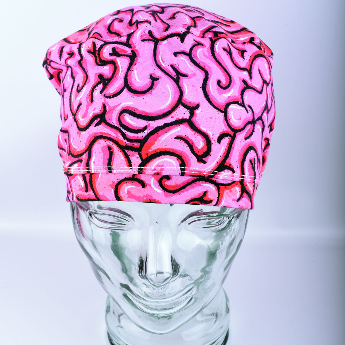 Pink brain-patterned surgical cap on a mannequin head against a light gray background