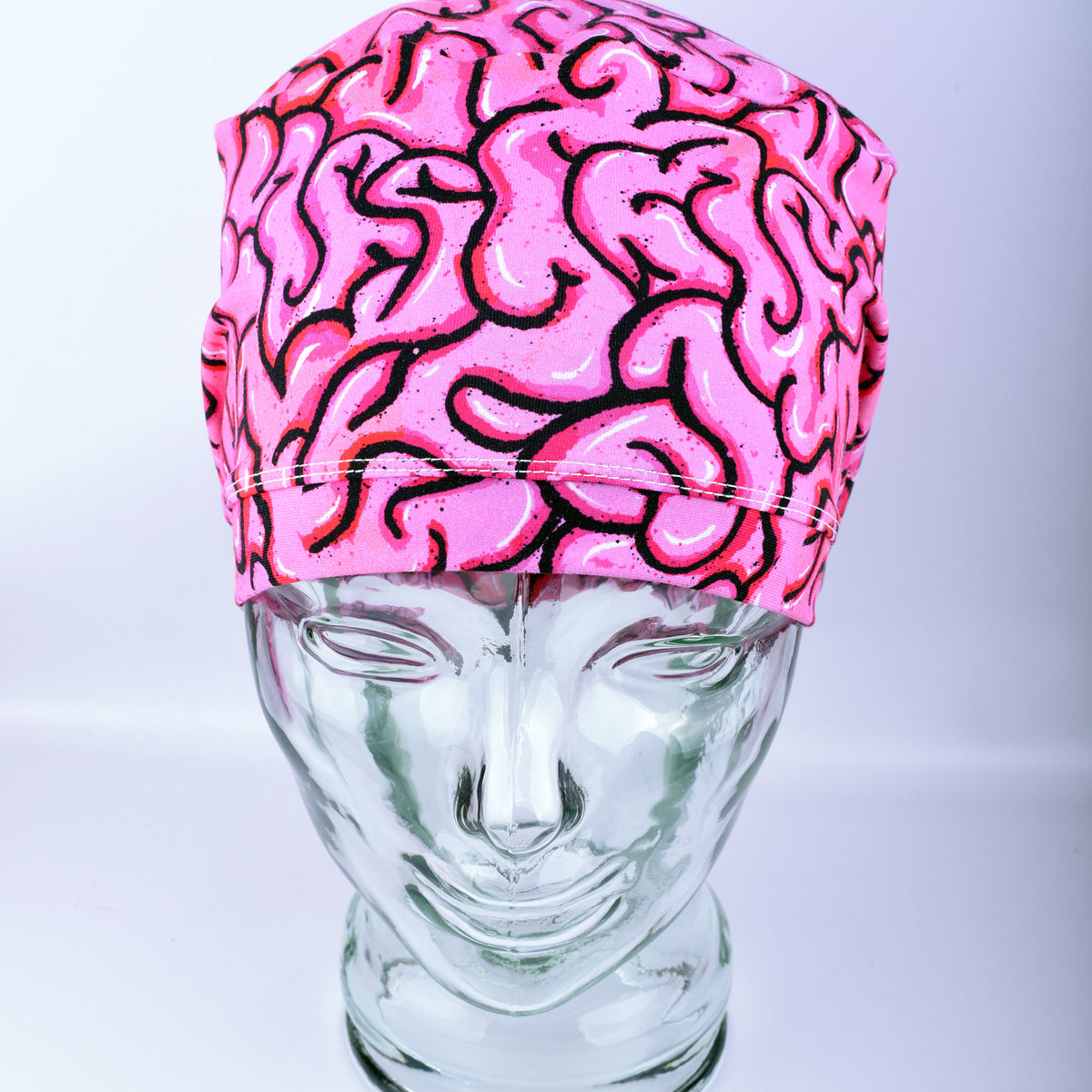 Pink brain-patterned scrub cap on a clear mannequin head against a white background