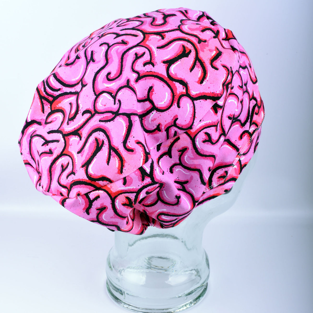 Pink brain scrub hat on a clear stand against a white background