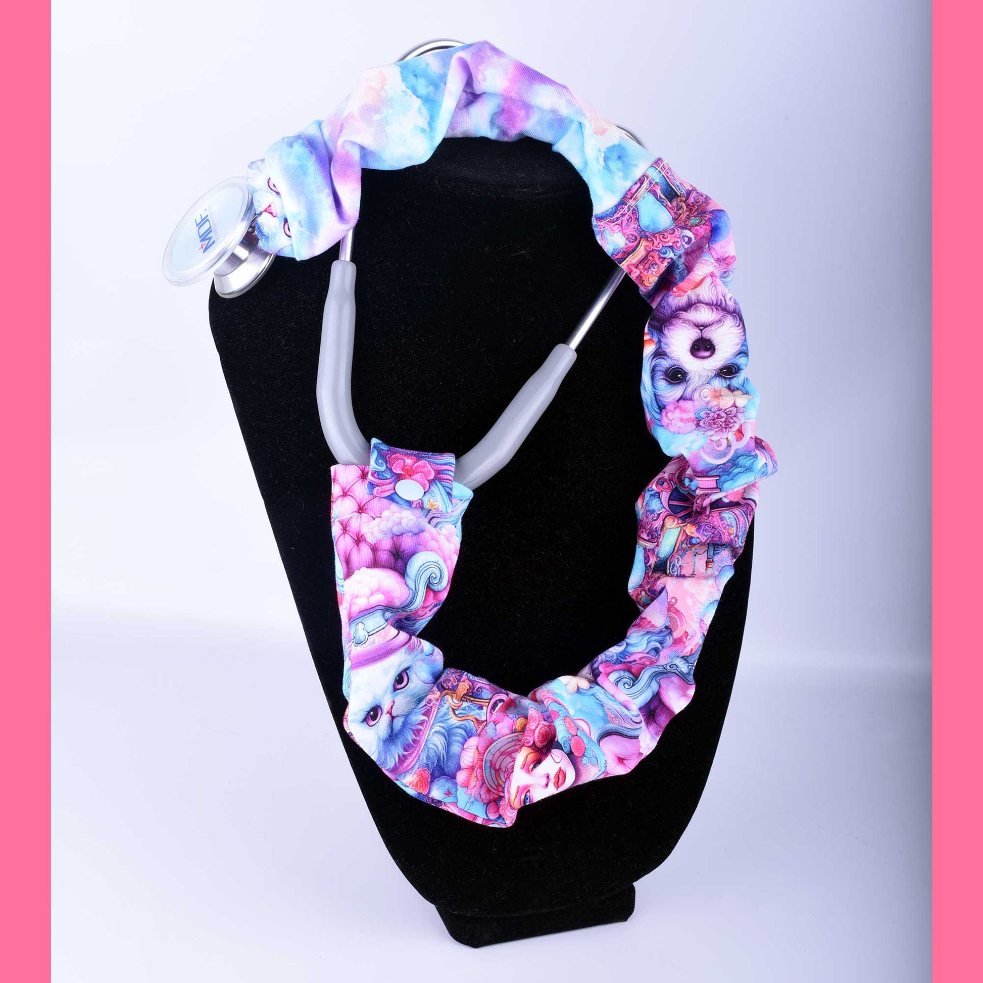 Hand-crafted pink and blue stethoscope cover featuring dogs, cats, and women. The fabric sleeve is shown fitted over a stethoscope tubing with a secure plastic snap closure.