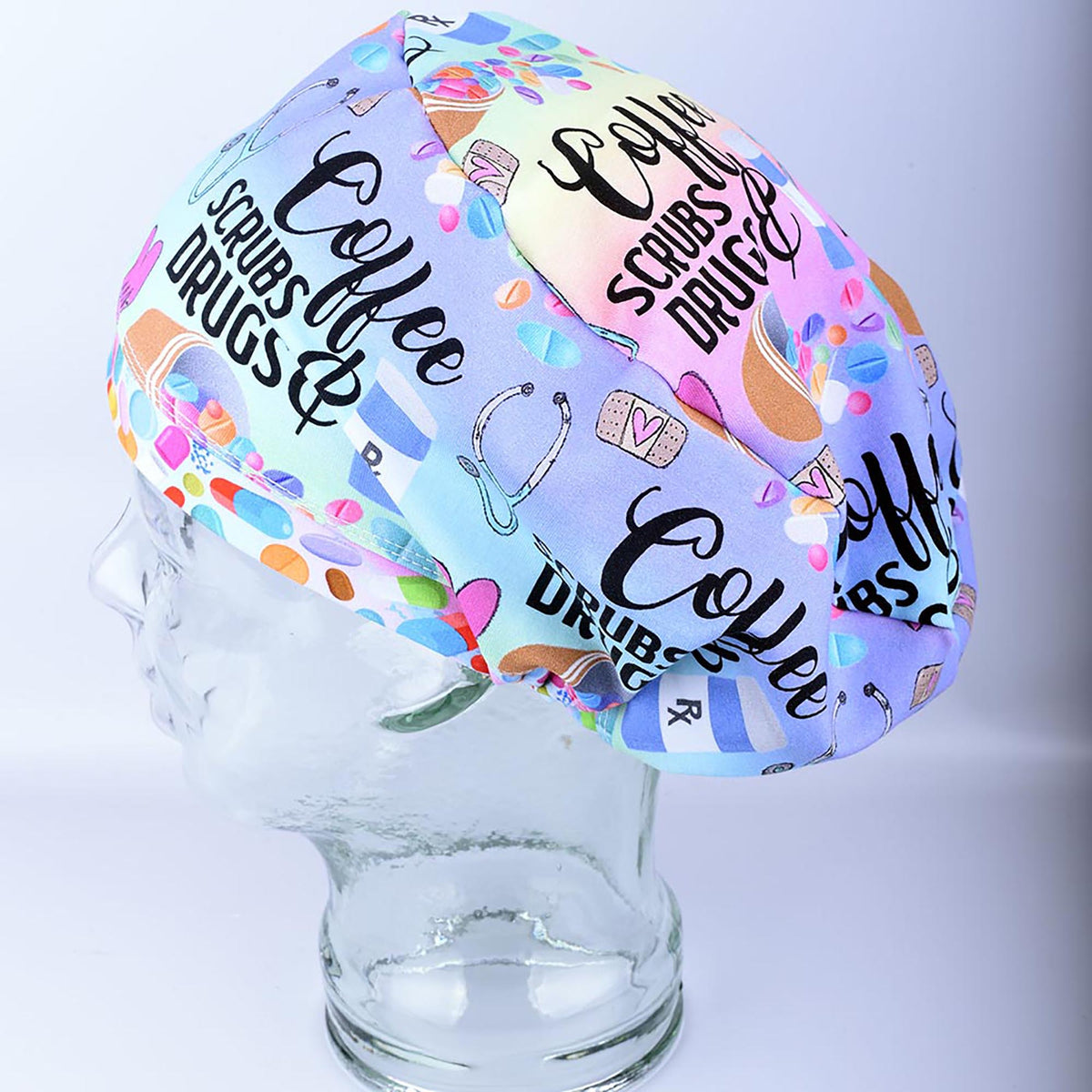 Euro-style full coverage scrub cap featuring a custom 'Coffee Scrubs Drugs' print on a white background, displayed on a glass mannequin head.