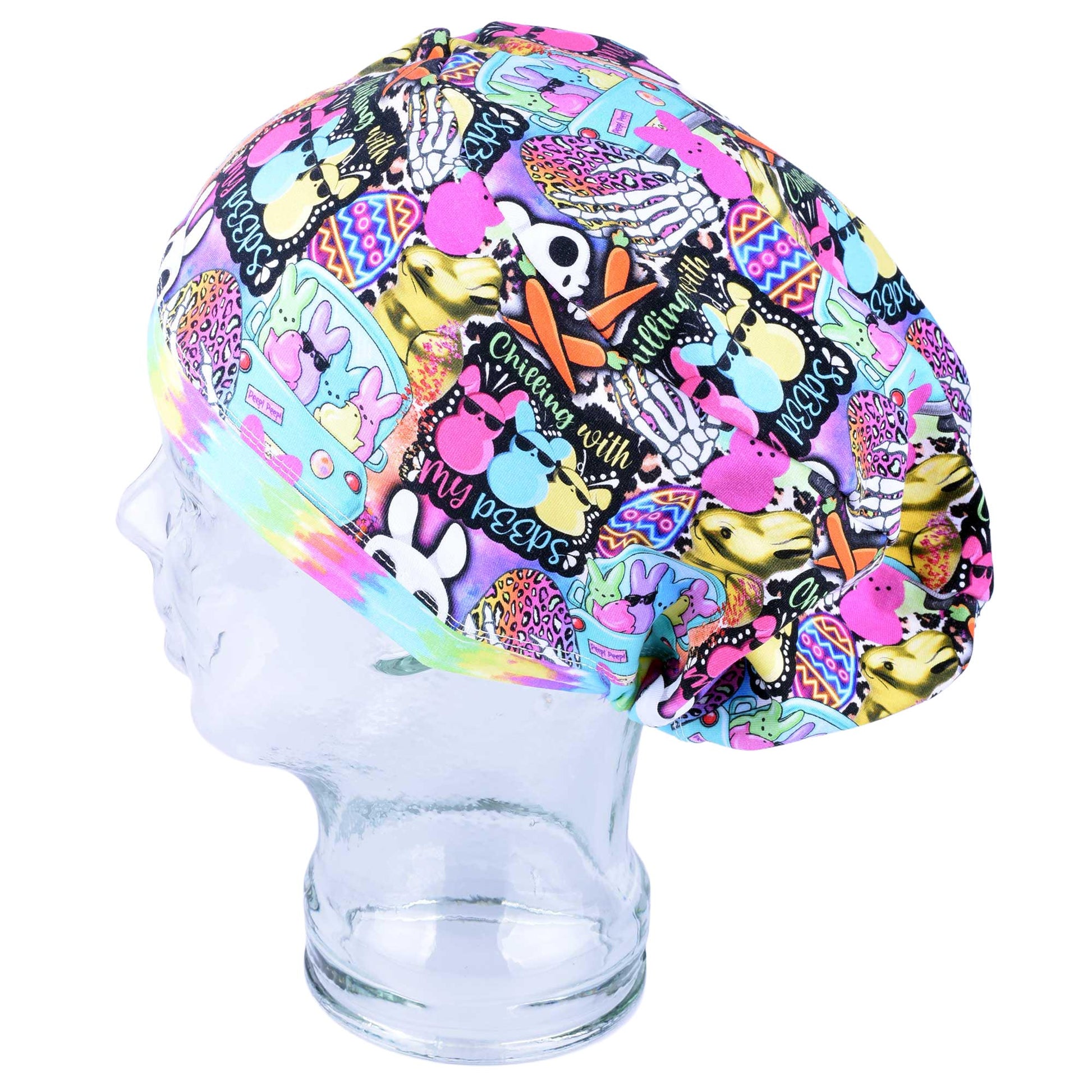 Colorful Easter scrub cap for women featuring a vibrant bunny, chick, and floral print on a black background. Handmade full-coverage surgical hat for nurses and doctors.