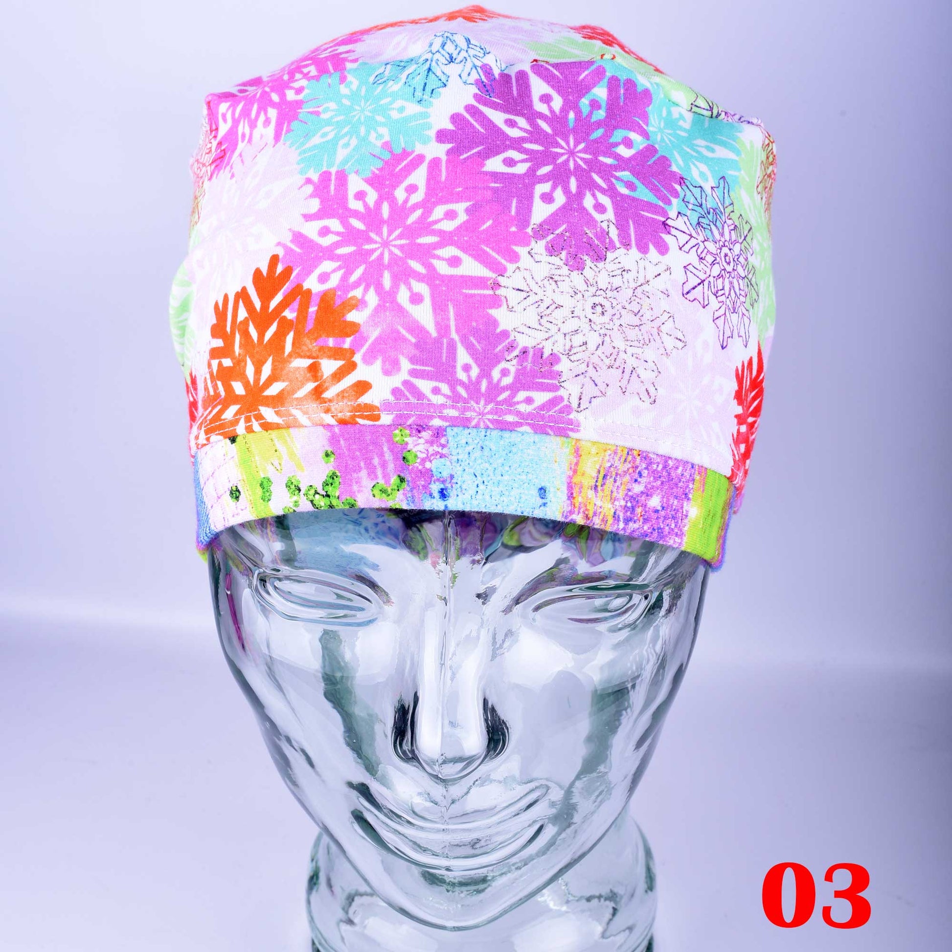 Front view of the Colorful Snowflakes Full Coverage Scrub Cap on a clear mannequin head, highlighting the vibrant neon holiday snowflake pattern, Euro style fit, and contrasting solid yellow band.