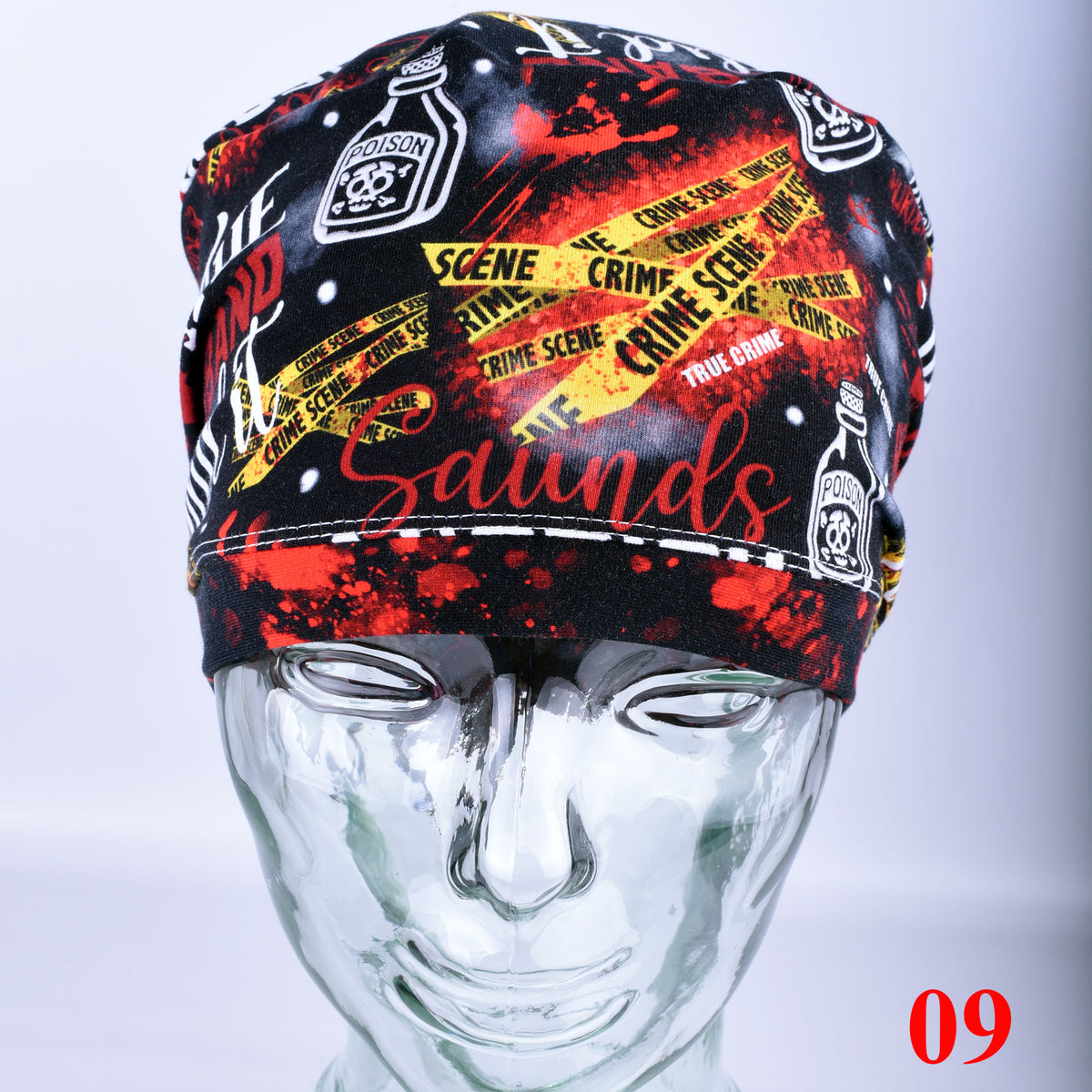 A black and red patterned scrub cap with yellow crime scene tape graphics and the word 'Sounds' in red script, displayed on a clear mannequin head against a light gray background.