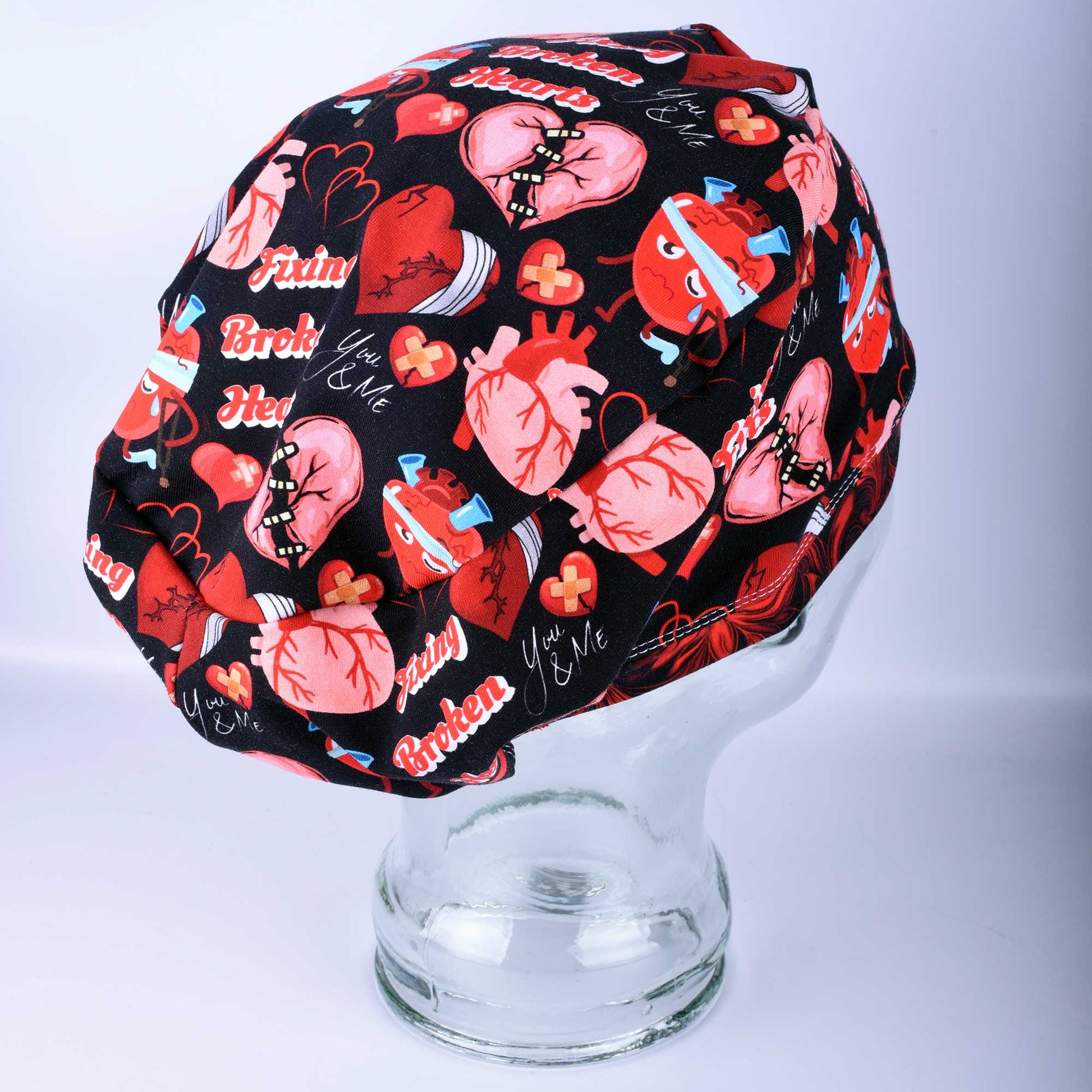 Full coverage Fixing Broken Hearts Scrub Cap with red and black heart medical pattern.