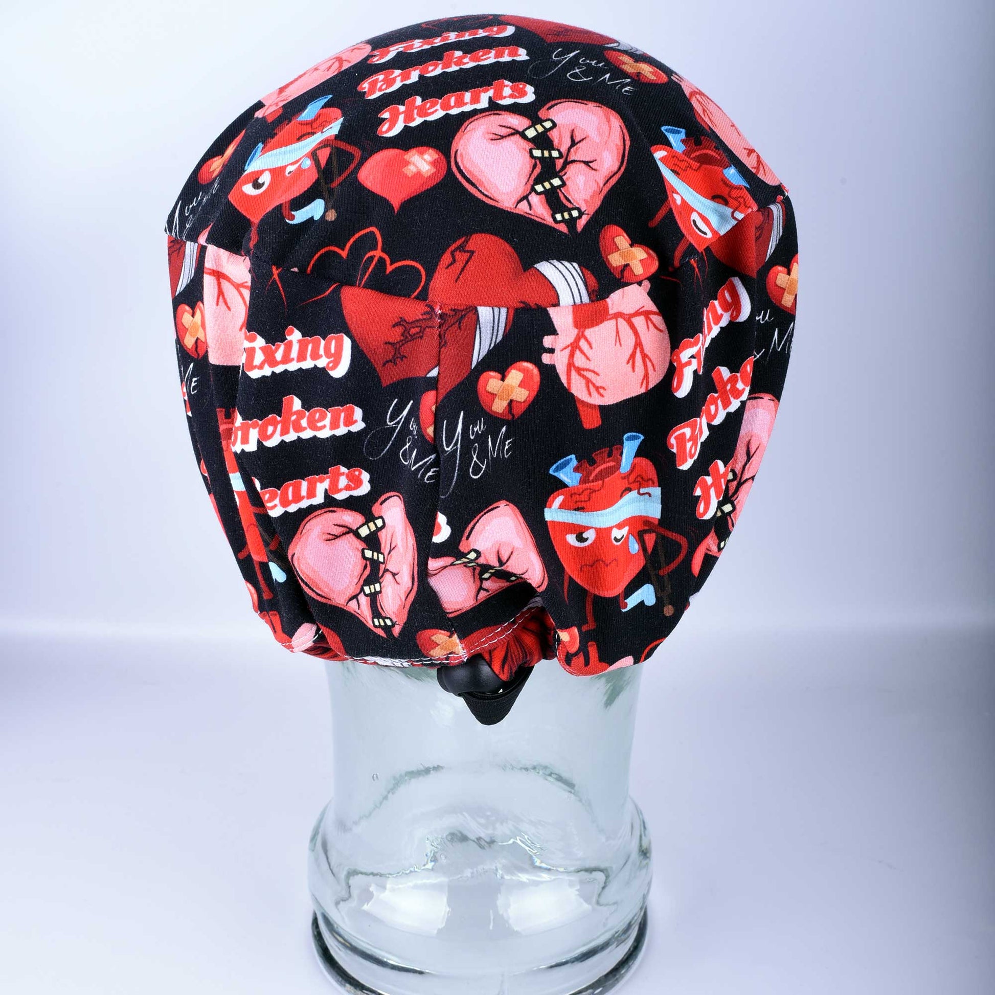 Full coverage Fixing Broken Hearts Scrub Cap with red and black heart medical pattern.