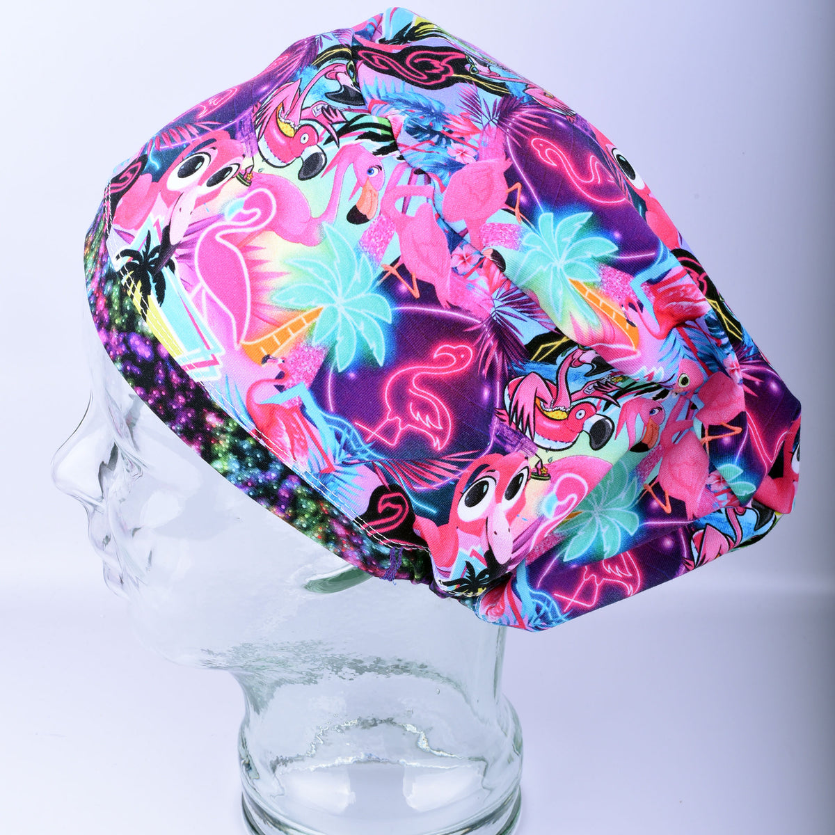 Handmade full coverage scrub cap featuring a vibrant neon pink flamingo and tropical floral print on a blue background.
