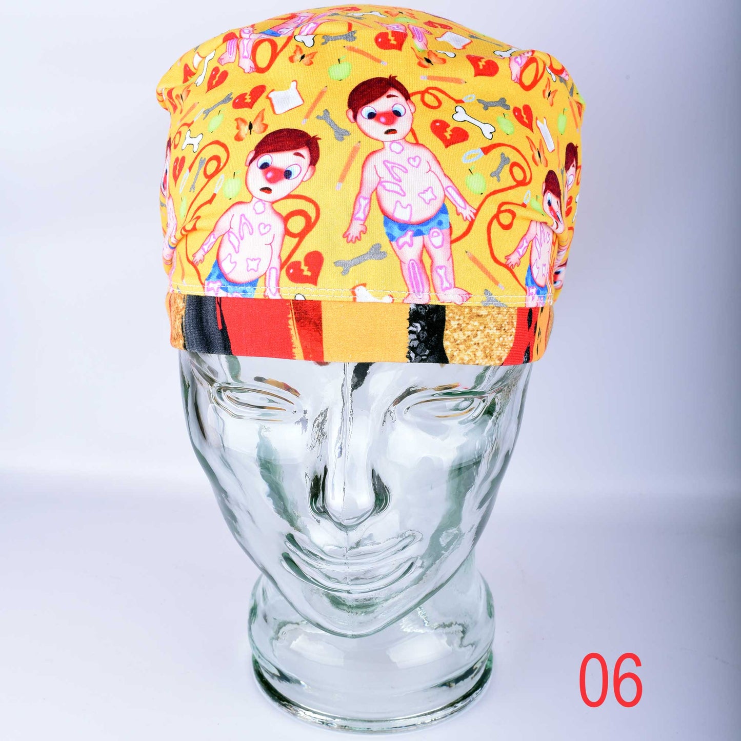 Colorful yellow scrub cap featuring cartoon medical patients and anatomical symbols on a glass mannequin head.