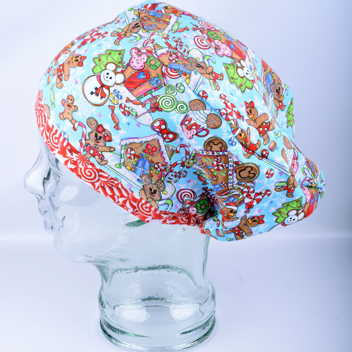 Full-coverage Euro-style medical hat featuring a festive blue holiday pattern with colorful gingerbread characters and candy illustrations, displayed on a mannequin head.