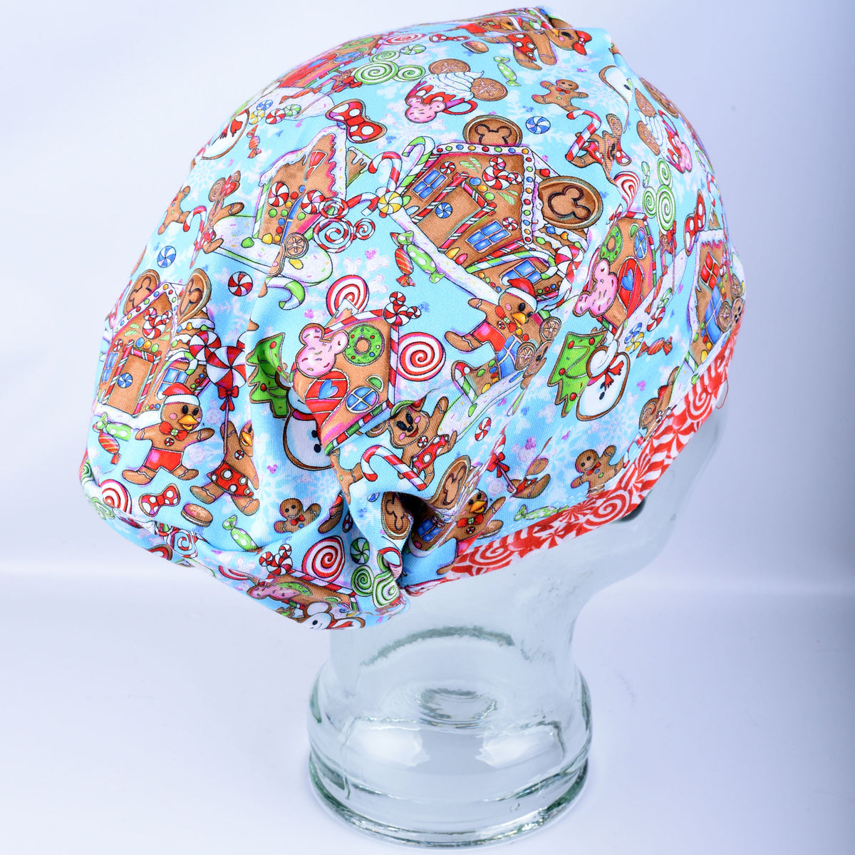 Full-coverage Euro-style medical hat featuring a festive blue holiday pattern with colorful gingerbread characters and candy illustrations, displayed on a mannequin head.