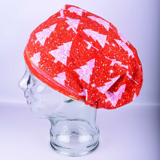Red scrub cap with white glittery Christmas tree pattern worn on a clear display head, side view showing full coverage fit.