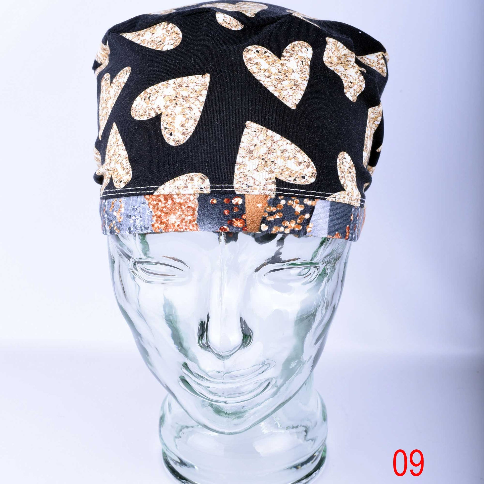 Front view of a European style surgical hat with gold hearts, showing the full hair coverage and soft stretch fit for medical professionals.