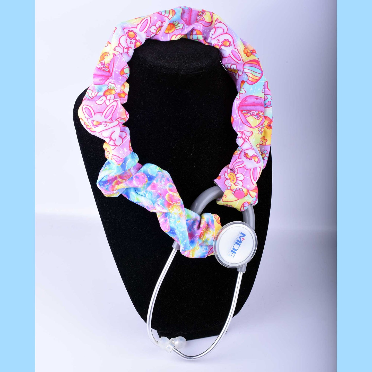 Groovy Easter stethoscope cover featuring a retro bunny and floral print in pink, purple, and orange on a soft cotton sleeve.
