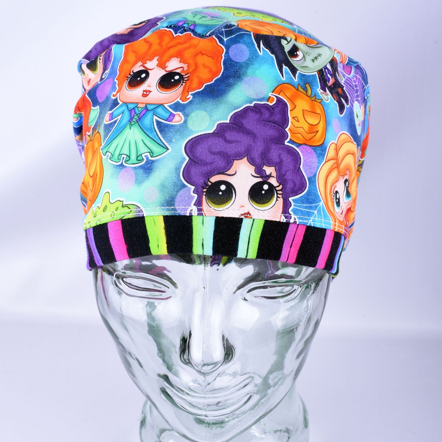 A colorful medical scrub cap featuring cartoon character prints, displayed on a clear plastic mannequin head against a light gray background.