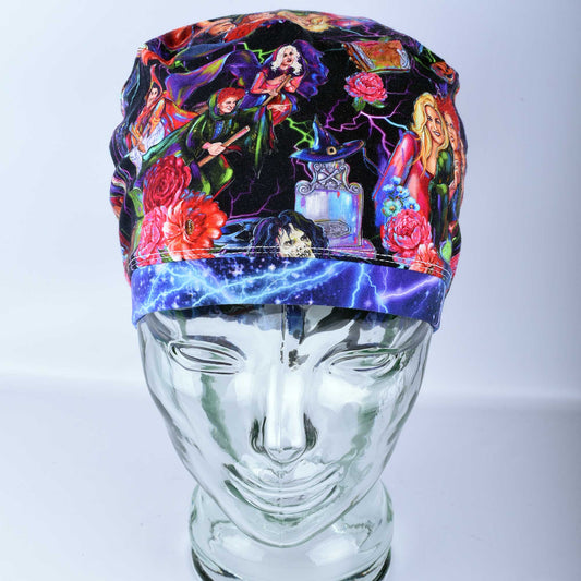 Front view of the Halloween Sisters medical scrub cap on a clear mannequin, showcasing the full-coverage fit and continuous spooky character print across the front brim.