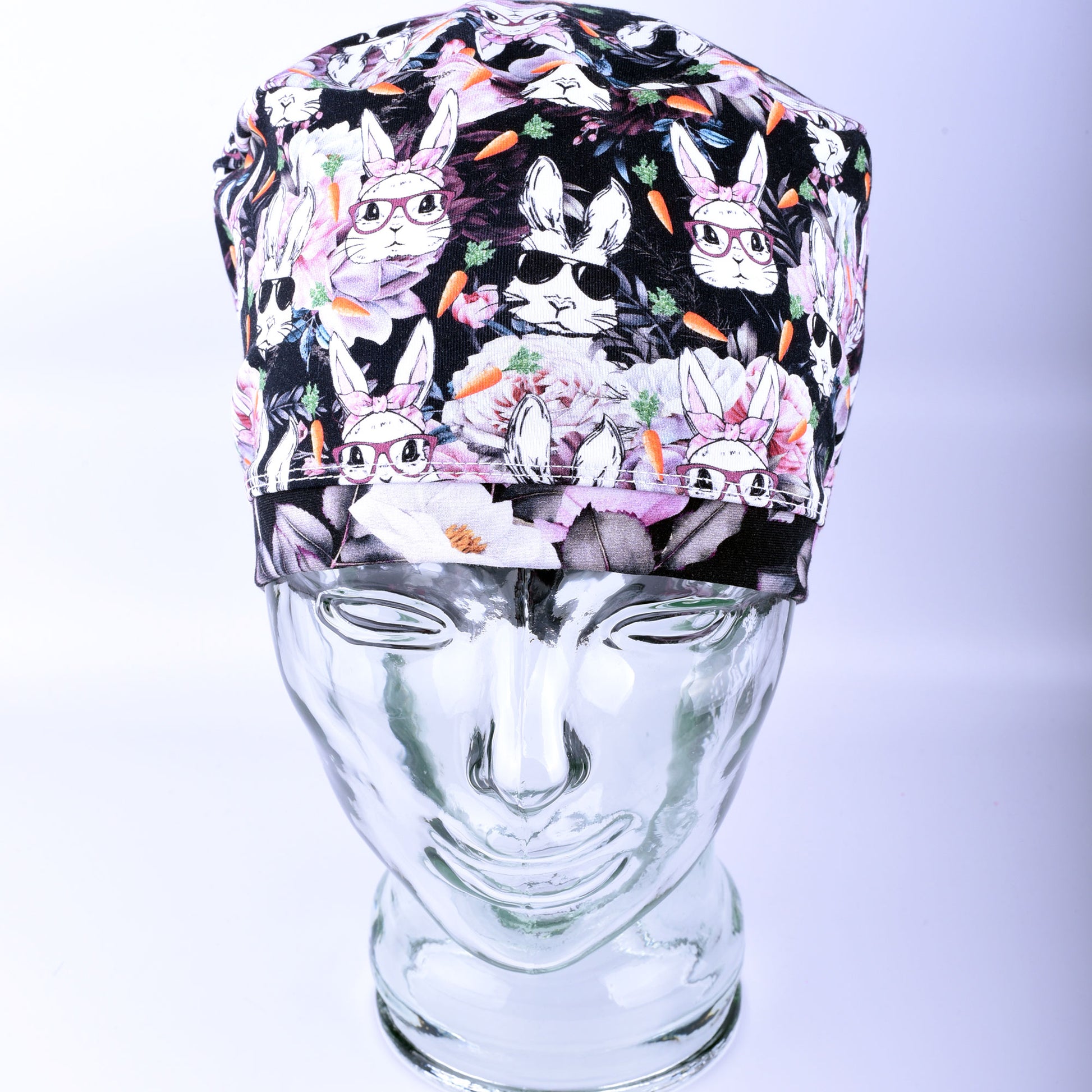 Front view of a stretchy knit scrub hat with a wide comfort band and vibrant rabbit illustration.