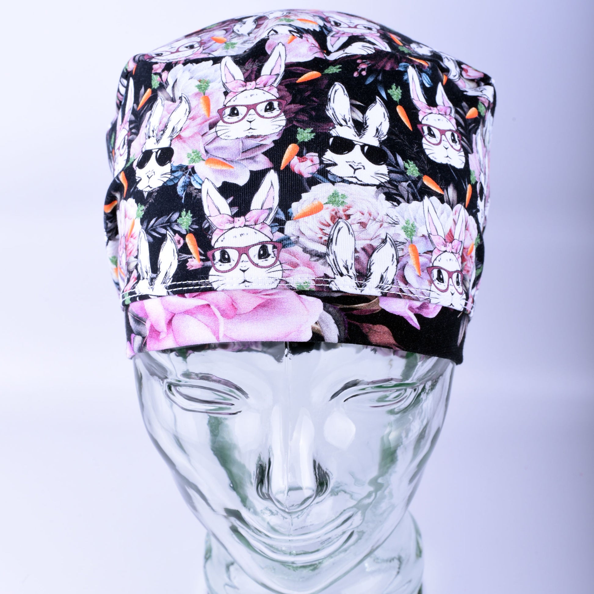 Front view of a stretchy knit scrub hat with a wide comfort band and vibrant rabbit illustration, shown on a mannequin.