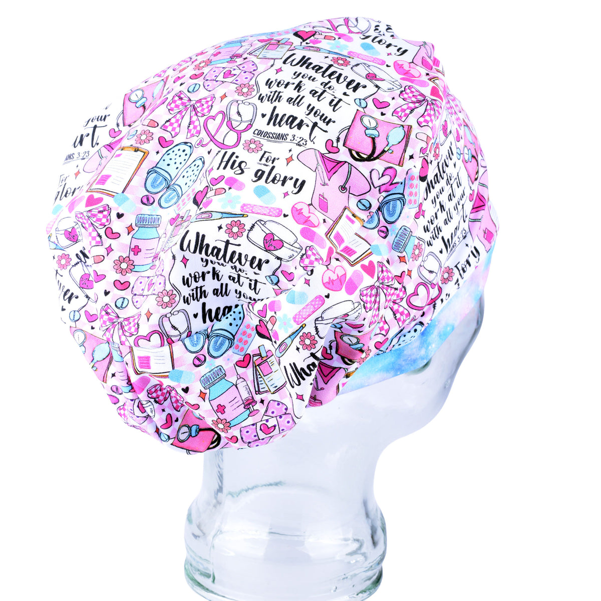 A pink and white scrubs cap with a colorful cartoon illustration pattern and motivational text, displayed on a clear glass mannequin head against a white background.