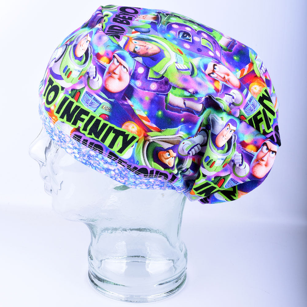Side view of a full-coverage surgical scrub cap on a clear mannequin head, featuring a vibrant cartoon astronaut and outer space pattern on a crisp white background