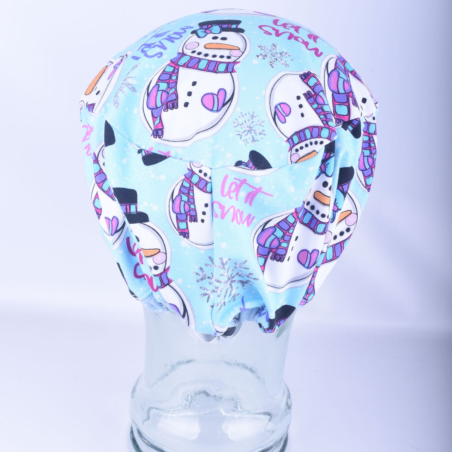 Close-up back view of the adjustable snowman scrub cap, highlighting the encased elastic band and heavy-duty black cord lock toggle used to customize the fit.