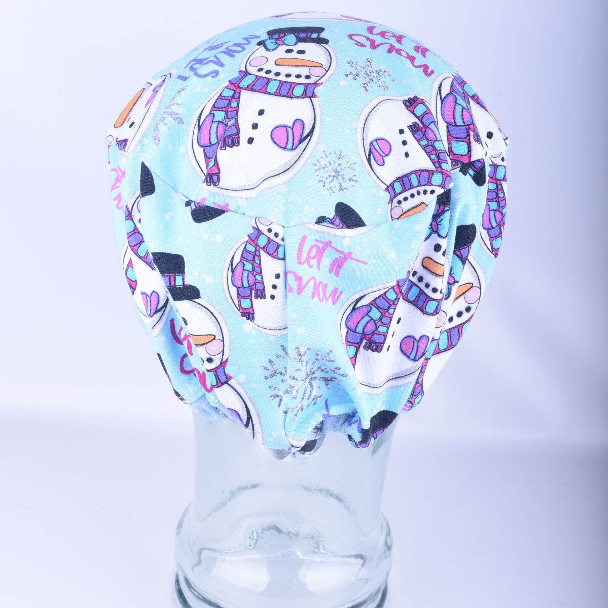 Close-up back view of the adjustable snowman scrub cap, highlighting the encased elastic band and heavy-duty black cord lock toggle used to customize the fit.