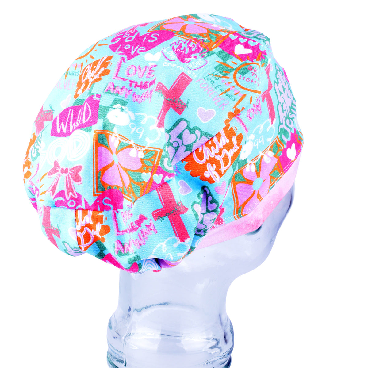 A light blue scrubs cap with a vibrant pink, orange, and green graphic collage print, displayed on a clear plastic mannequin head against a white background.