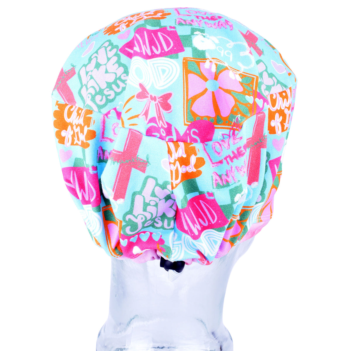Back view of a multicolor scrub cap with a busy graphic pattern featuring crosses, flowers, and text like 'WWJD' and 'Love THEM ANYWAY' on a light blue background, displayed on a clear mannequin head against a white background.