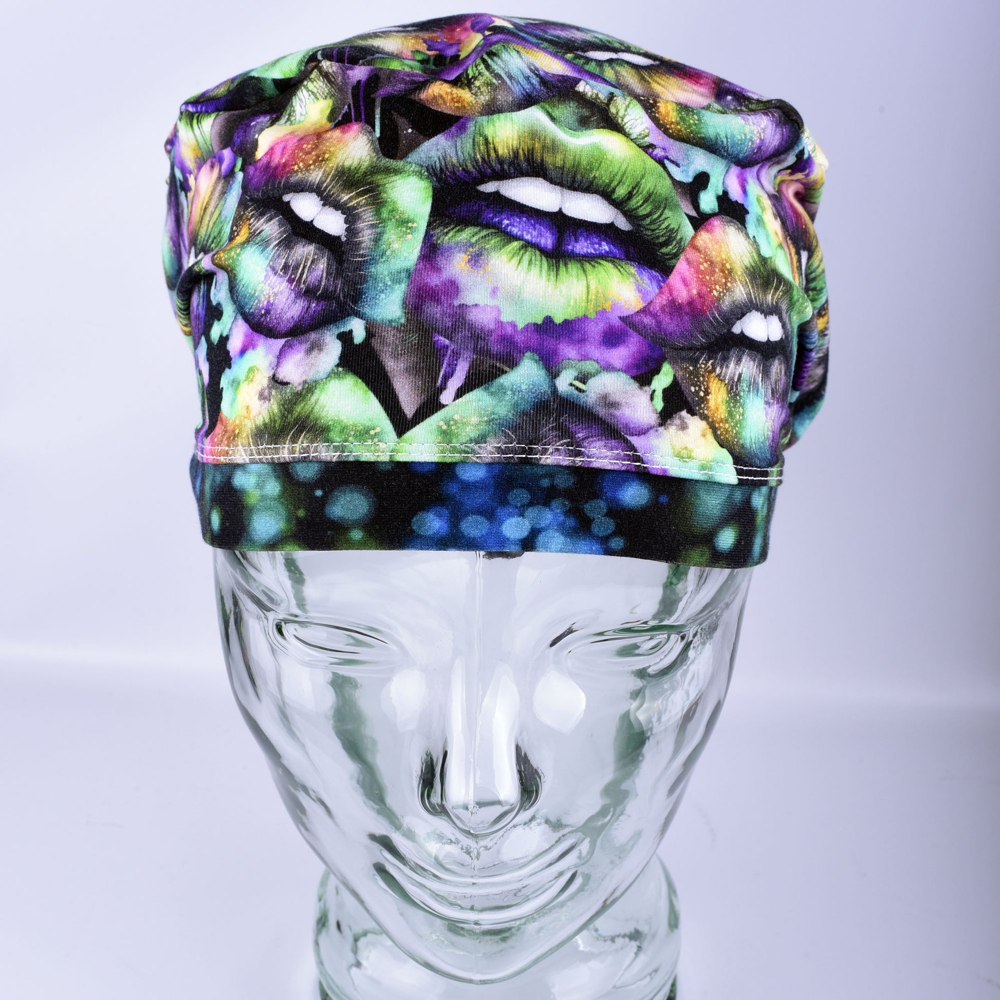 Full coverage Euro-style scrub cap featuring a festive Lucky Lips print with vibrant green, purple, and gold multicolor lips on a clean white background, displayed on a mannequin head to show a secure fit.