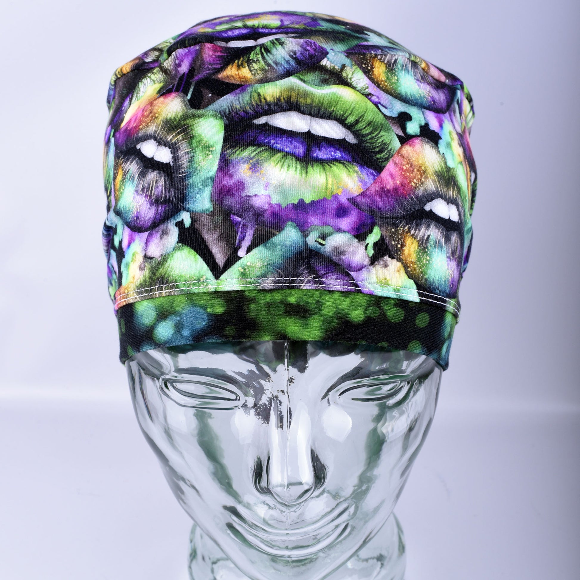 Full coverage Euro-style scrub cap featuring a festive Lucky Lips print with vibrant green, purple, and gold multicolor lips on a clean white background, displayed on a mannequin head to show a secure fit.