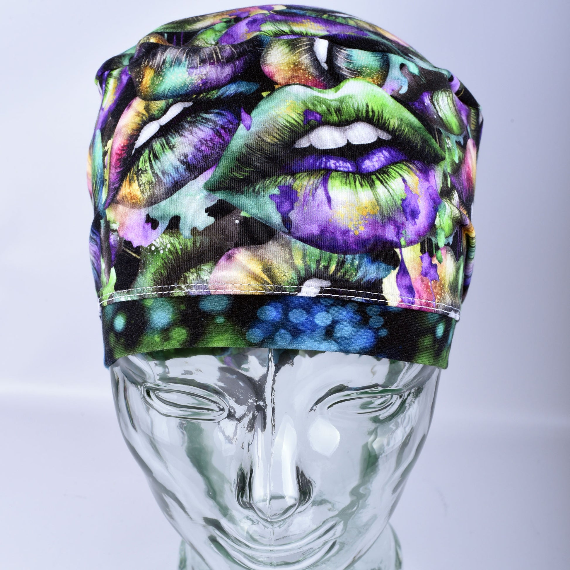 Full coverage Euro-style scrub cap featuring a festive Lucky Lips print with vibrant green, purple, and gold multicolor lips on a clean white background, displayed on a mannequin head to show a secure fit.