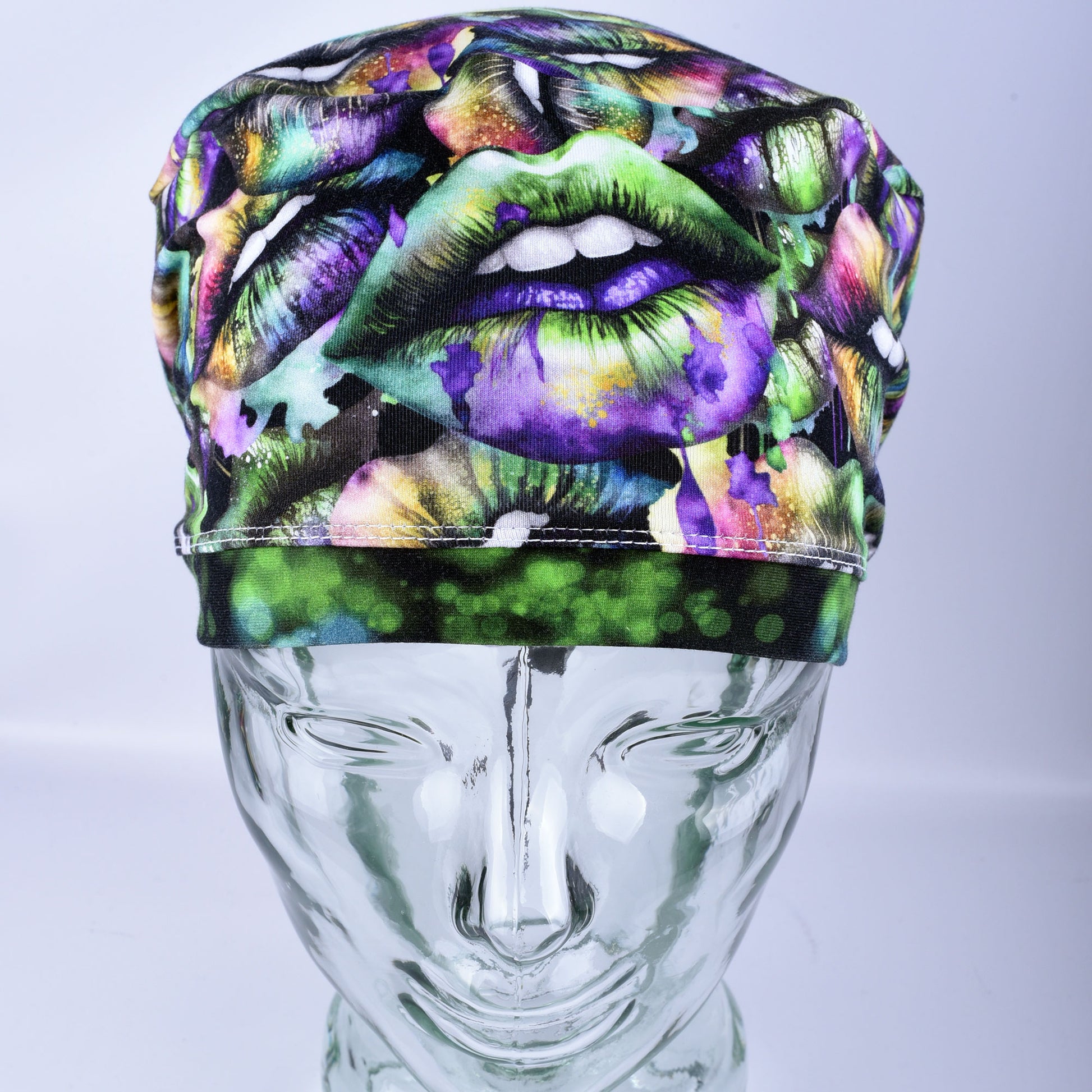 Full coverage Euro-style scrub cap featuring a festive Lucky Lips print with vibrant green, purple, and gold multicolor lips on a clean white background, displayed on a mannequin head to show a secure fit.