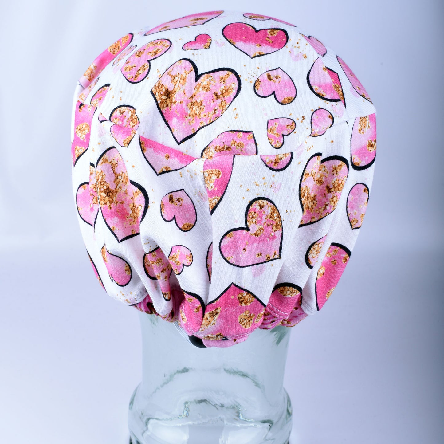 Close-up of the adjustable heavy-duty cord lock toggle and elastic back on the pink and gold hearts surgical hat.