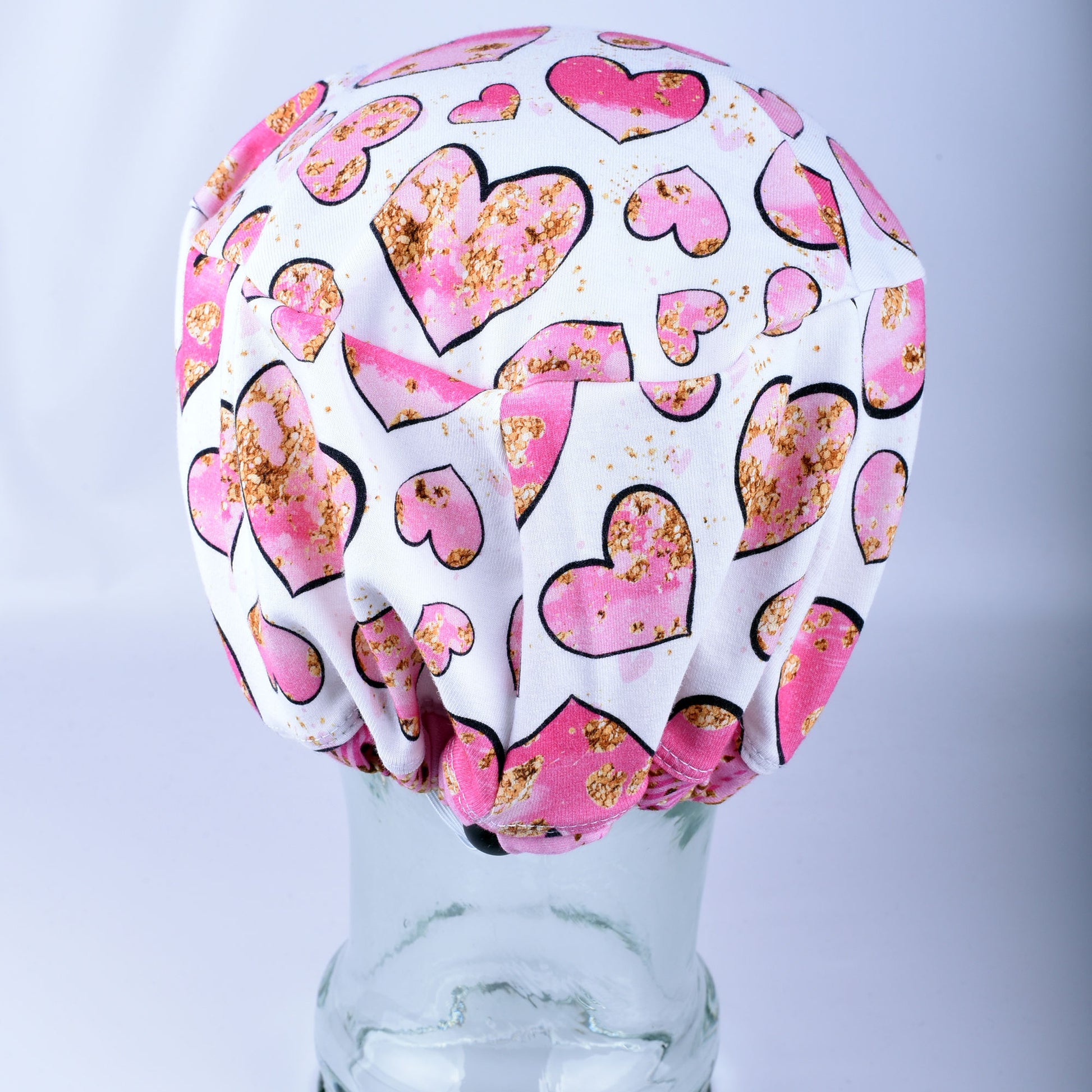 Close-up of the adjustable heavy-duty cord lock toggle and elastic back on the pink and gold hearts surgical hat.