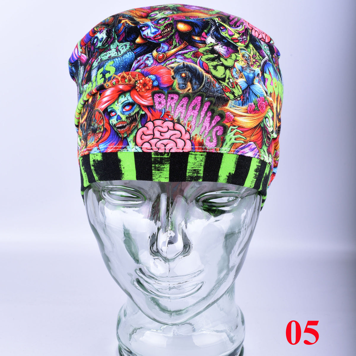 A multicolor psychedelic zombies and brains print scrub cap with a black and neon green striped brim, displayed on a clear glass mannequin head against a light gray background.
