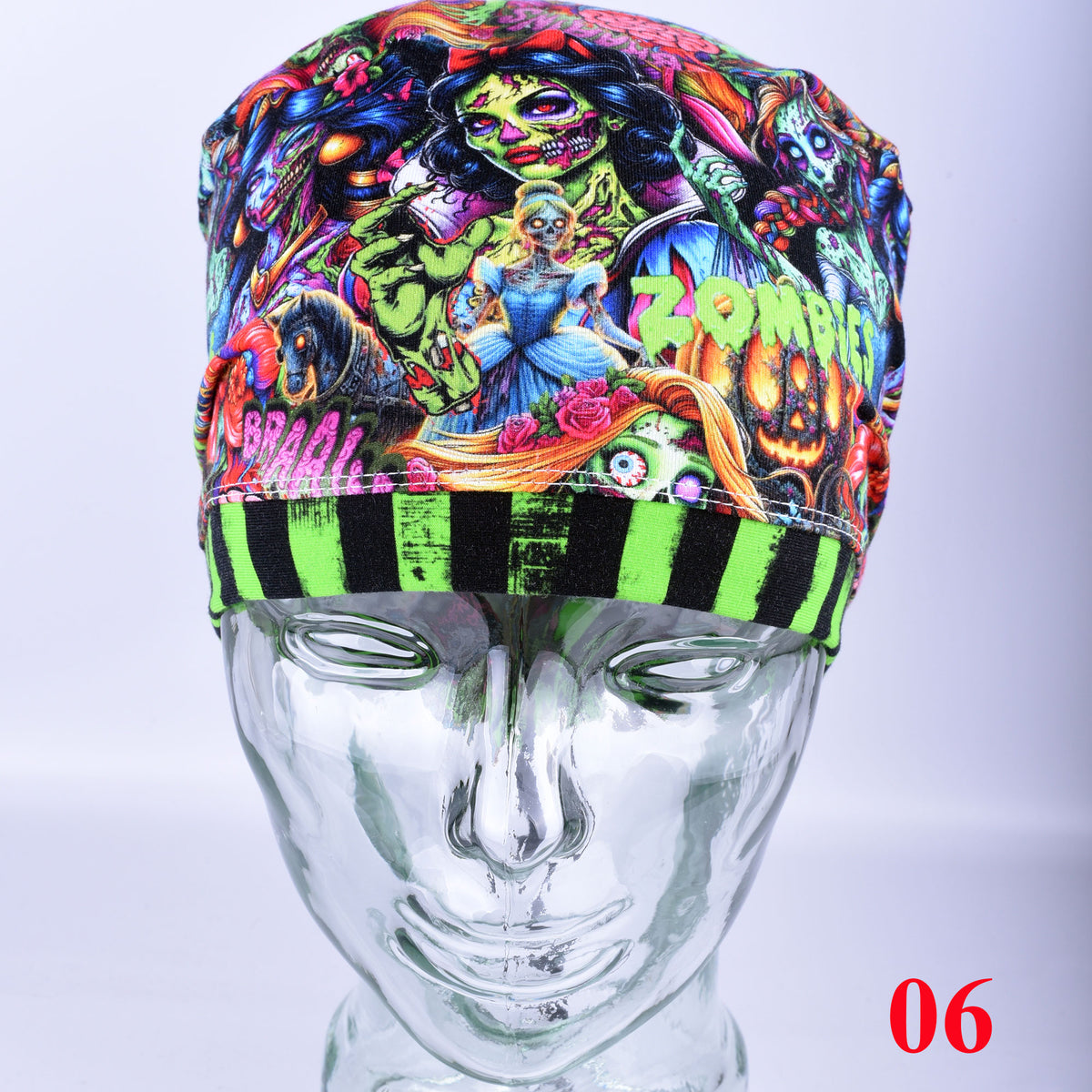 A colorful zombies and brains themed surgical scrub cap displayed on a metallic mannequin head. The cap features a vibrant, multi-colored graphic print with various zombie and horror character illustrations, along with a striped brim in neon green and black.