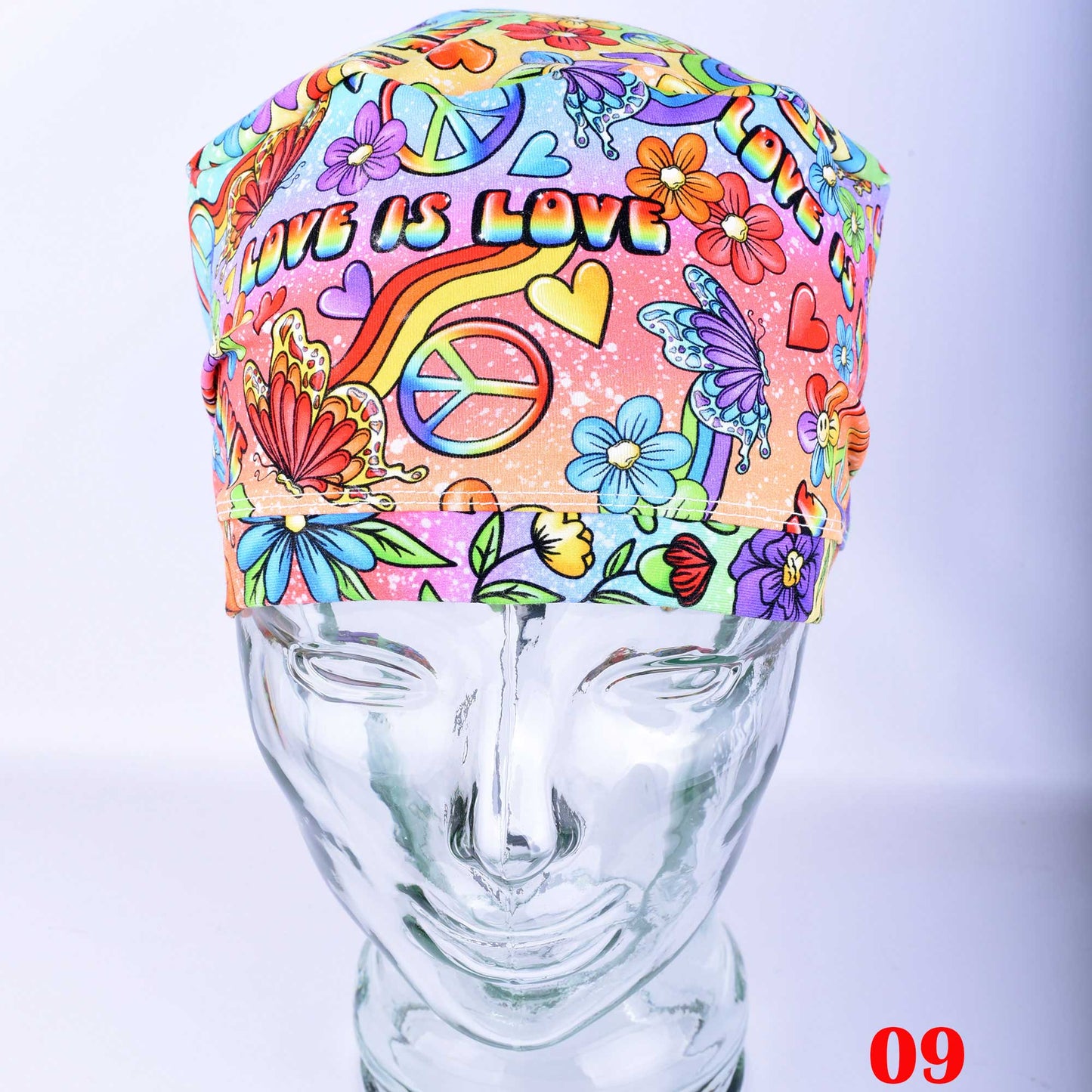 Close-up of Love is Love scrub cap Design 09 showing a dense, colorful rainbow 'Love' typography print for healthcare professionals.
